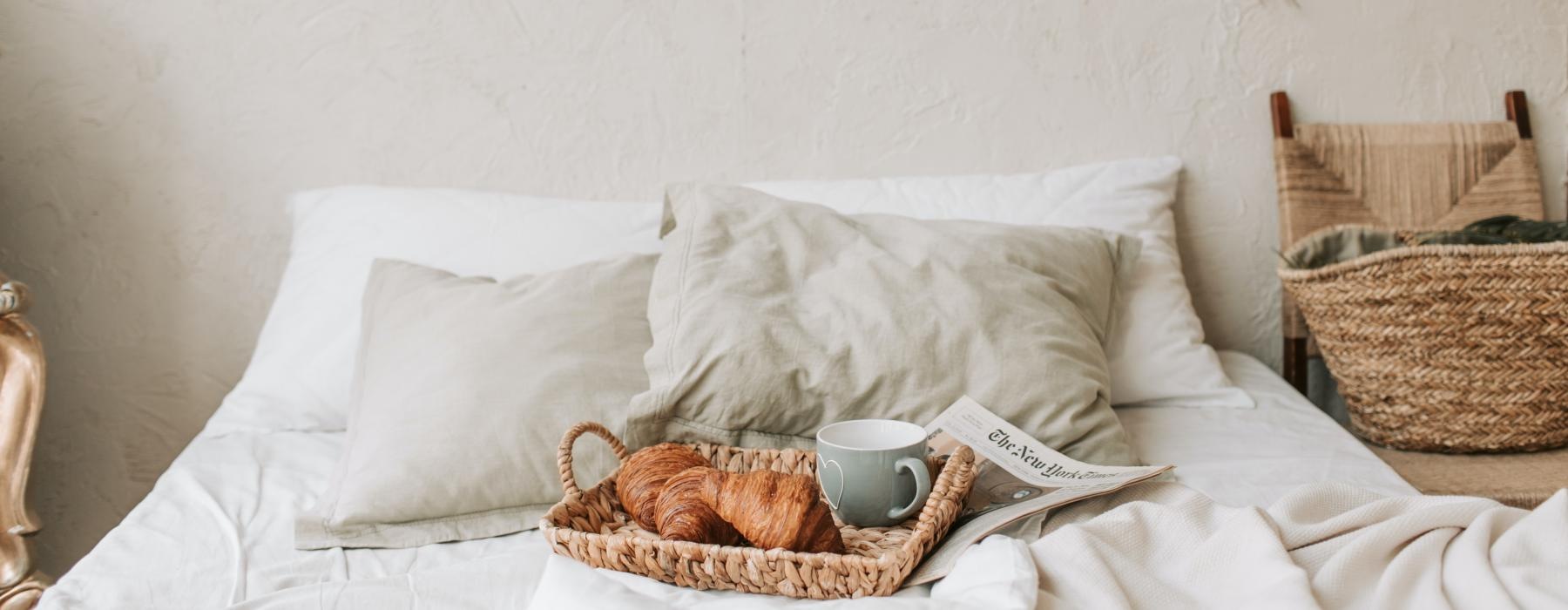 a bed with a cup of coffee and a book on it