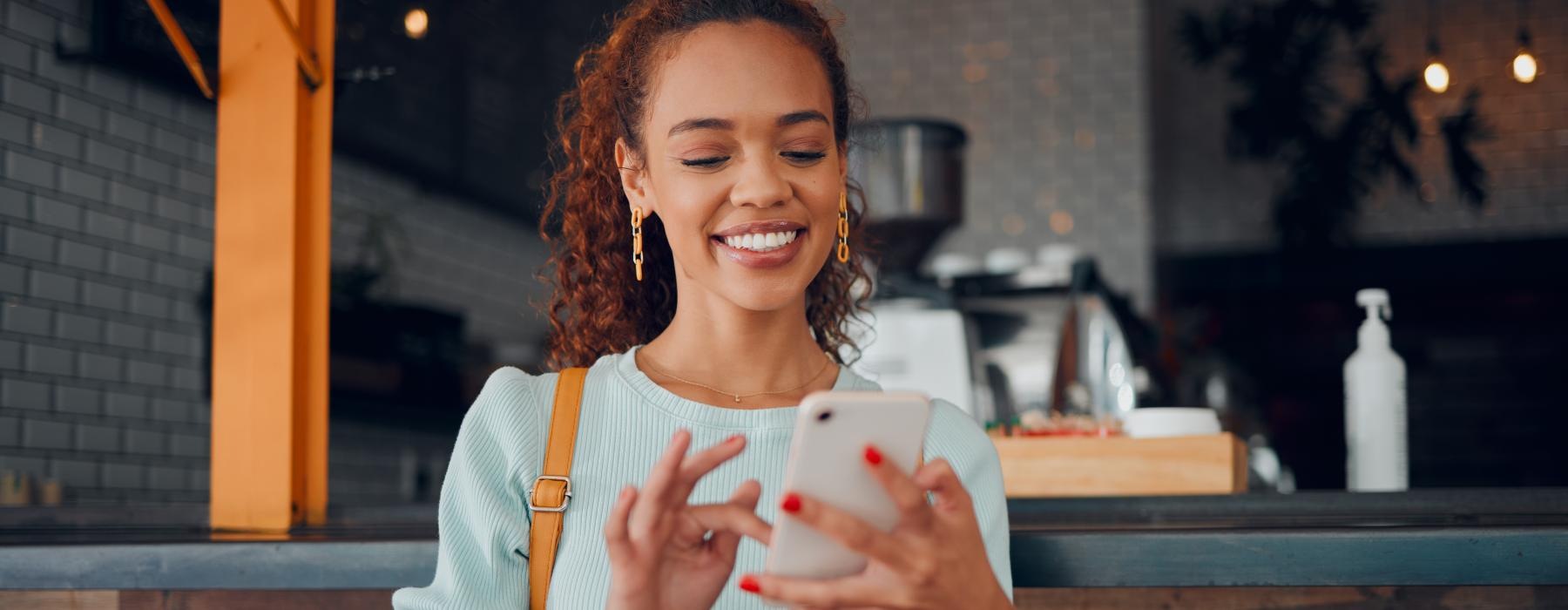 a woman holding a cup and looking at a cell phone